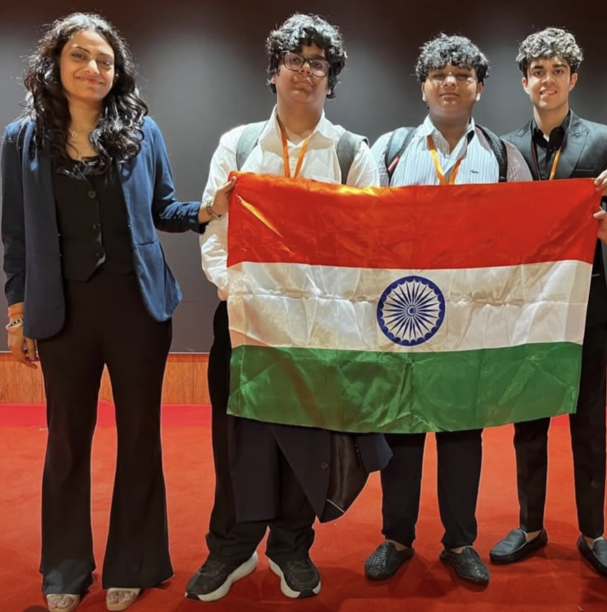 Smyan Bansal with his debating team holding the Indian flag